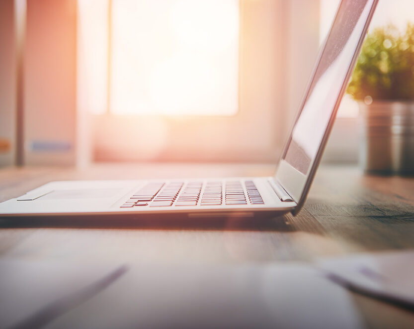 Laptop on the desk in front of a window with a plant. Ready for therapy with Nina Tomkiewicz, LCSW in San Diego, CA