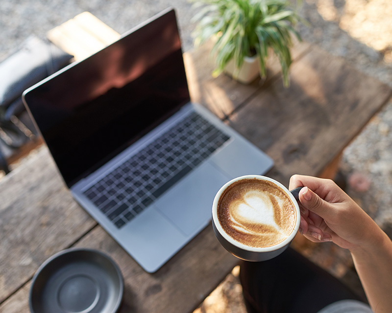 Laptop with a latte getting ready for online therapy with Nina. Learn about her therapeutic approach.