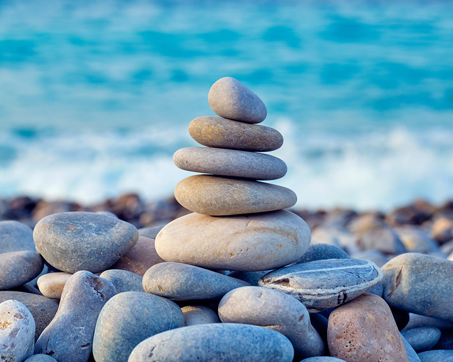 Zen rocks stacked in front of ocean in San Diego.