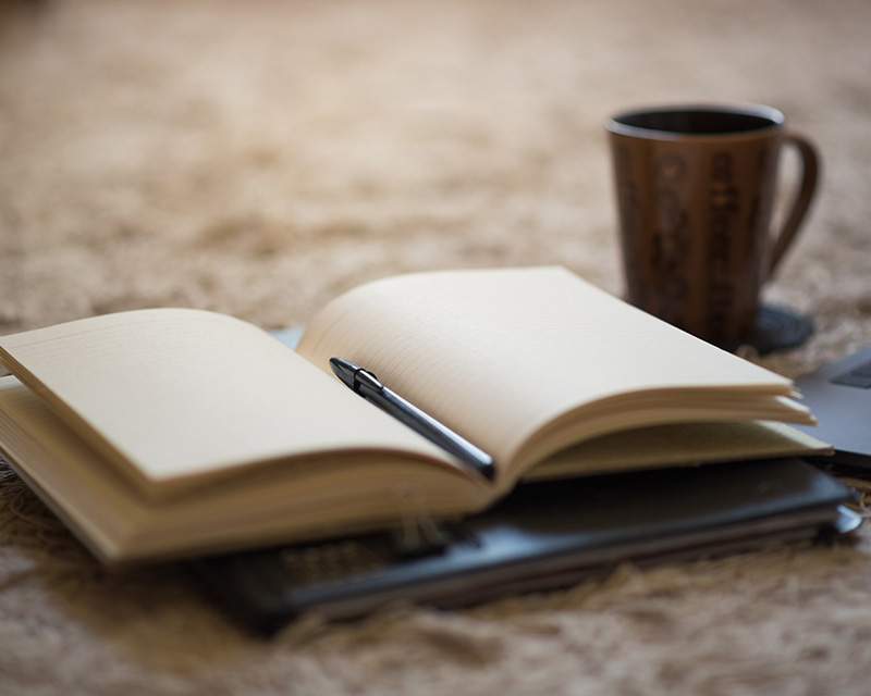 Open book on the table with a mug for therapy with Nina